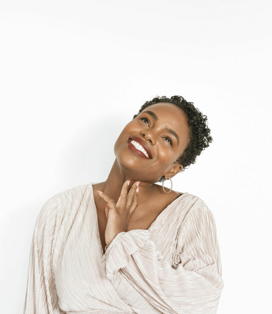 a woman smiling with her hand on her neck